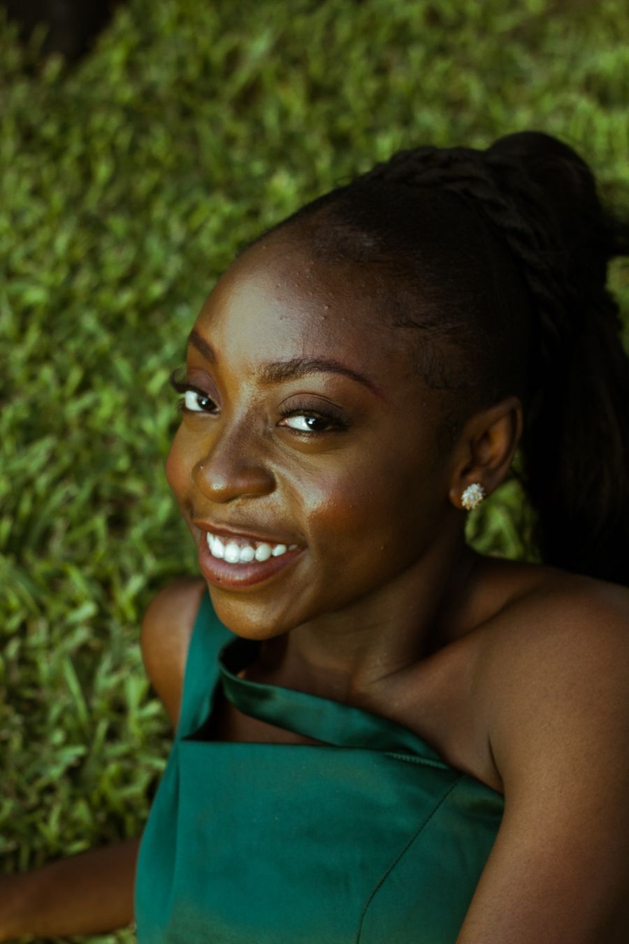 A woman in a green dress smiling against a grassy backdrop.