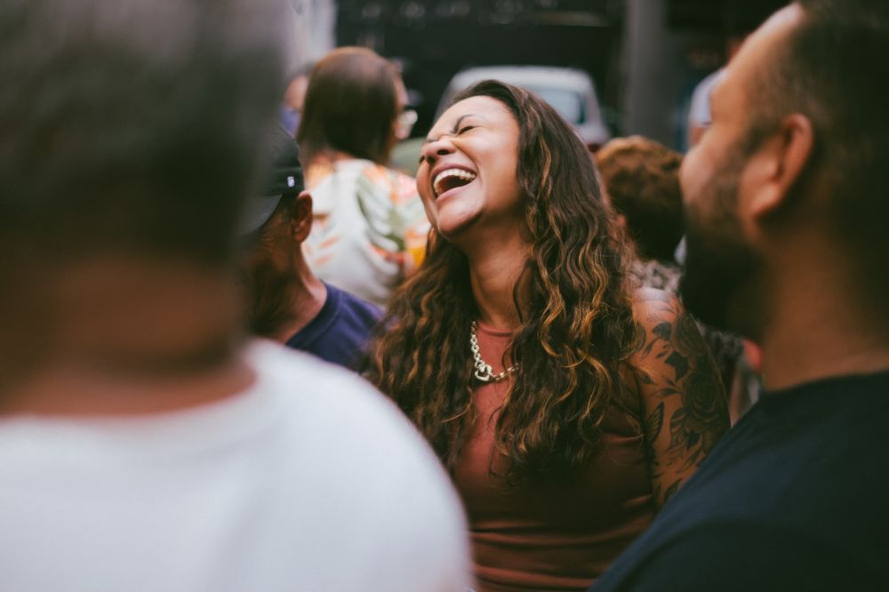 A woman laughing at a lively outdoor dinner.