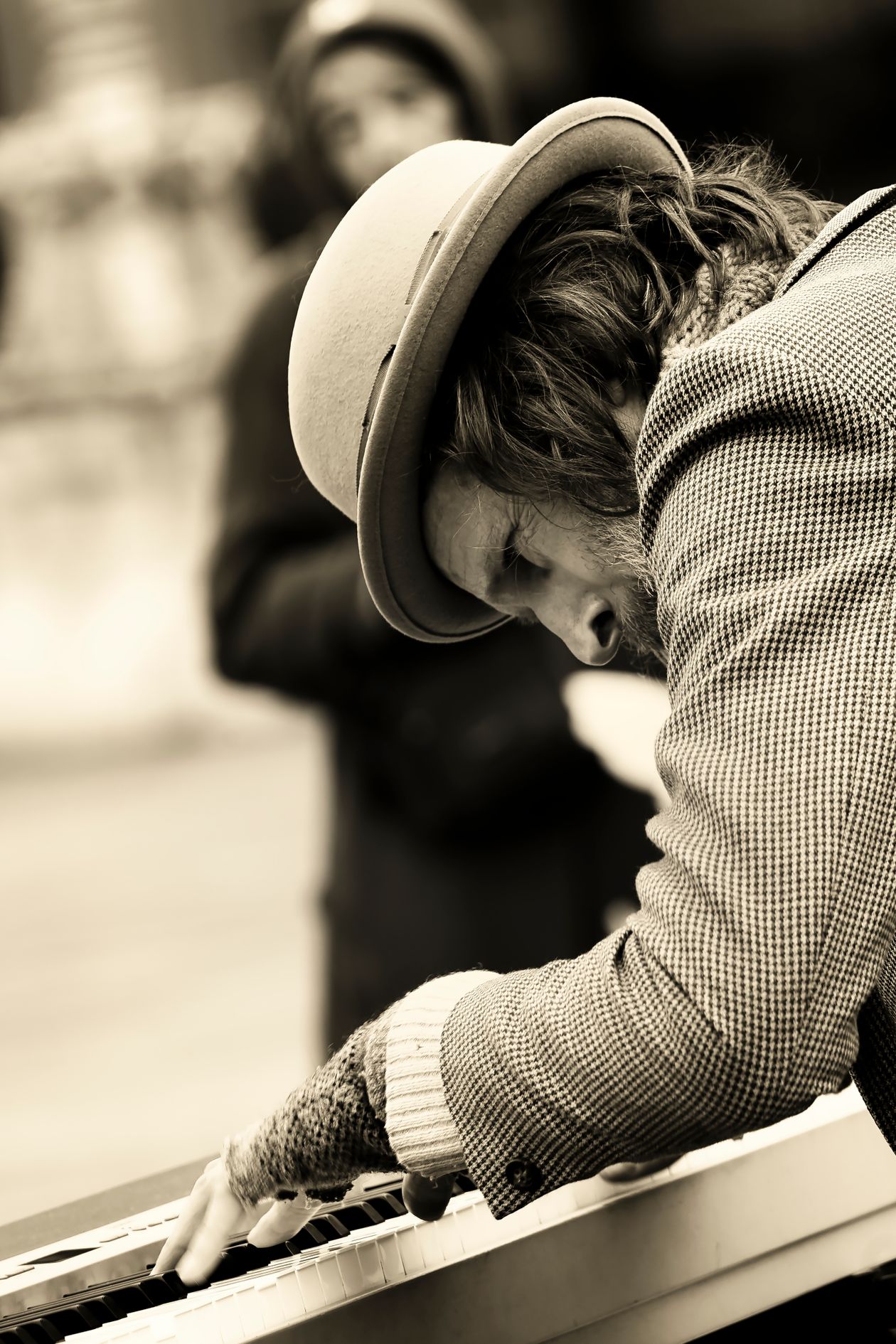 A street musician focused on a keyboard, sepia toned.